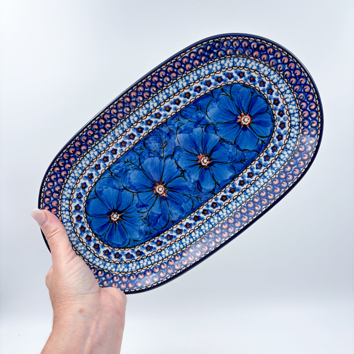 Cobalt Poppies oval platter held in hand, top-down view of full platter with blue poppy flowers