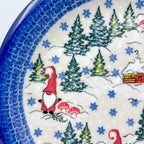 UNIKAT Gnome Village plate, close-up rim detail showing gnome, cabin, and pine trees in snow