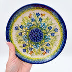 UNIKAT Bluebell Meadow plate held in hand, top-down view showing bluebell burst with bees