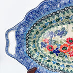 Iris Meadow oval platter with handles, close-up angled view of cutout handle and iris and poppy bouquet