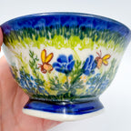 Bluebell Meadow small pedestal bowl, close-up side view held in hand showing bluebell florals and butterflies