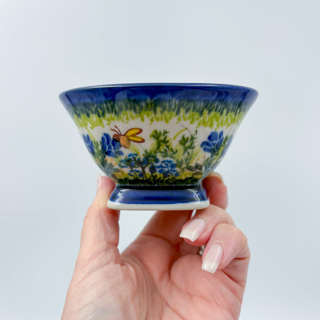 Bluebell Meadow small pedestal bowl held in hand showing blue florals and butterfly on green meadow band