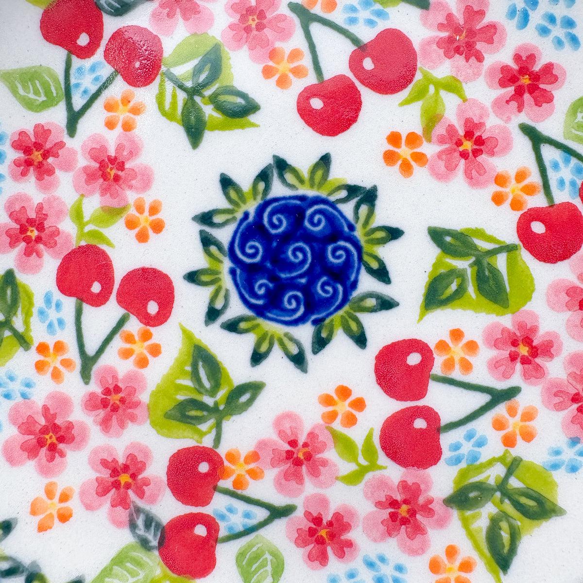UNIKAT Cherry Blossom plate, close-up top-down view of cherry and blossom pattern with blue spiral center