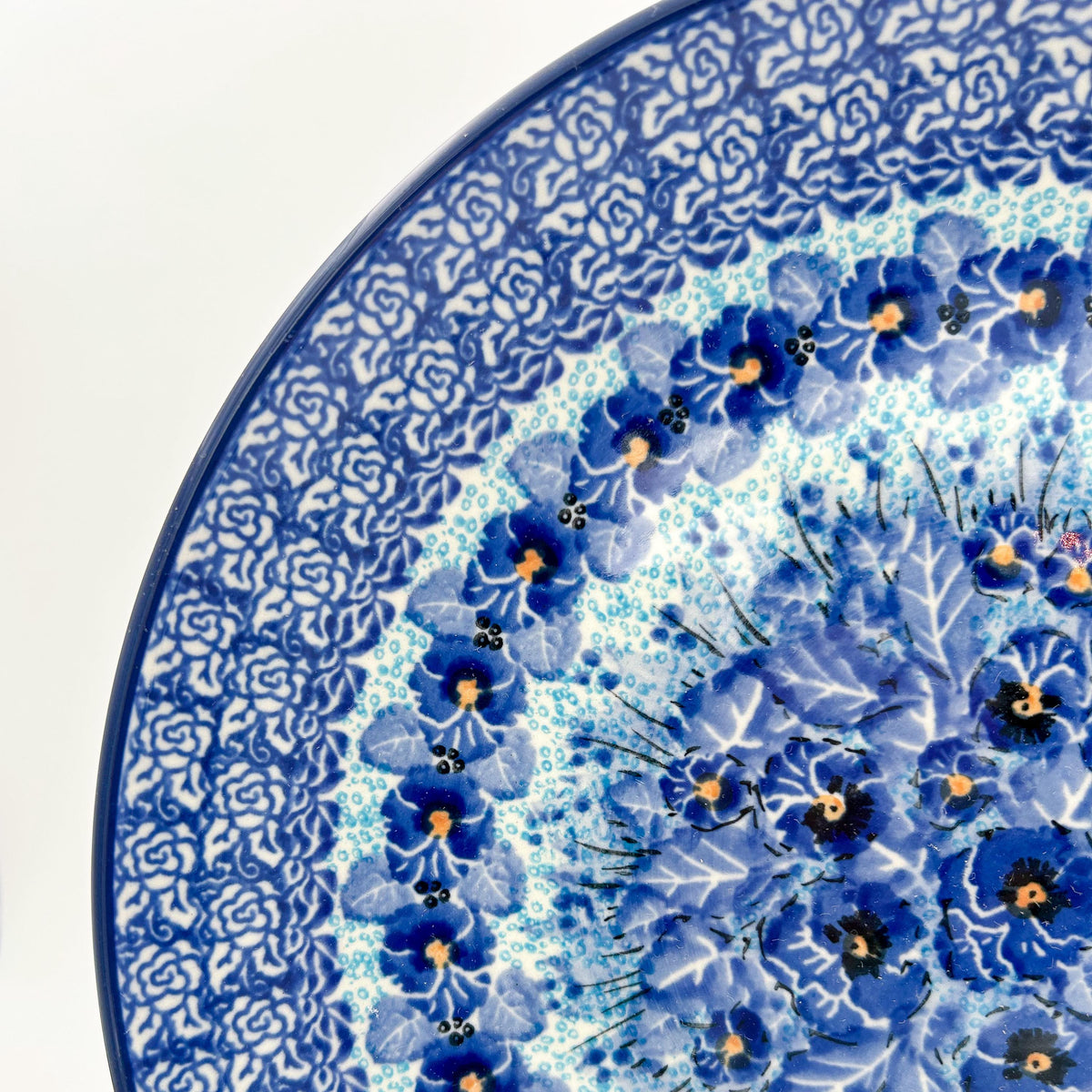 UNIKAT Deep Winter plate, close-up rim detail showing rose border and blue pansy ring