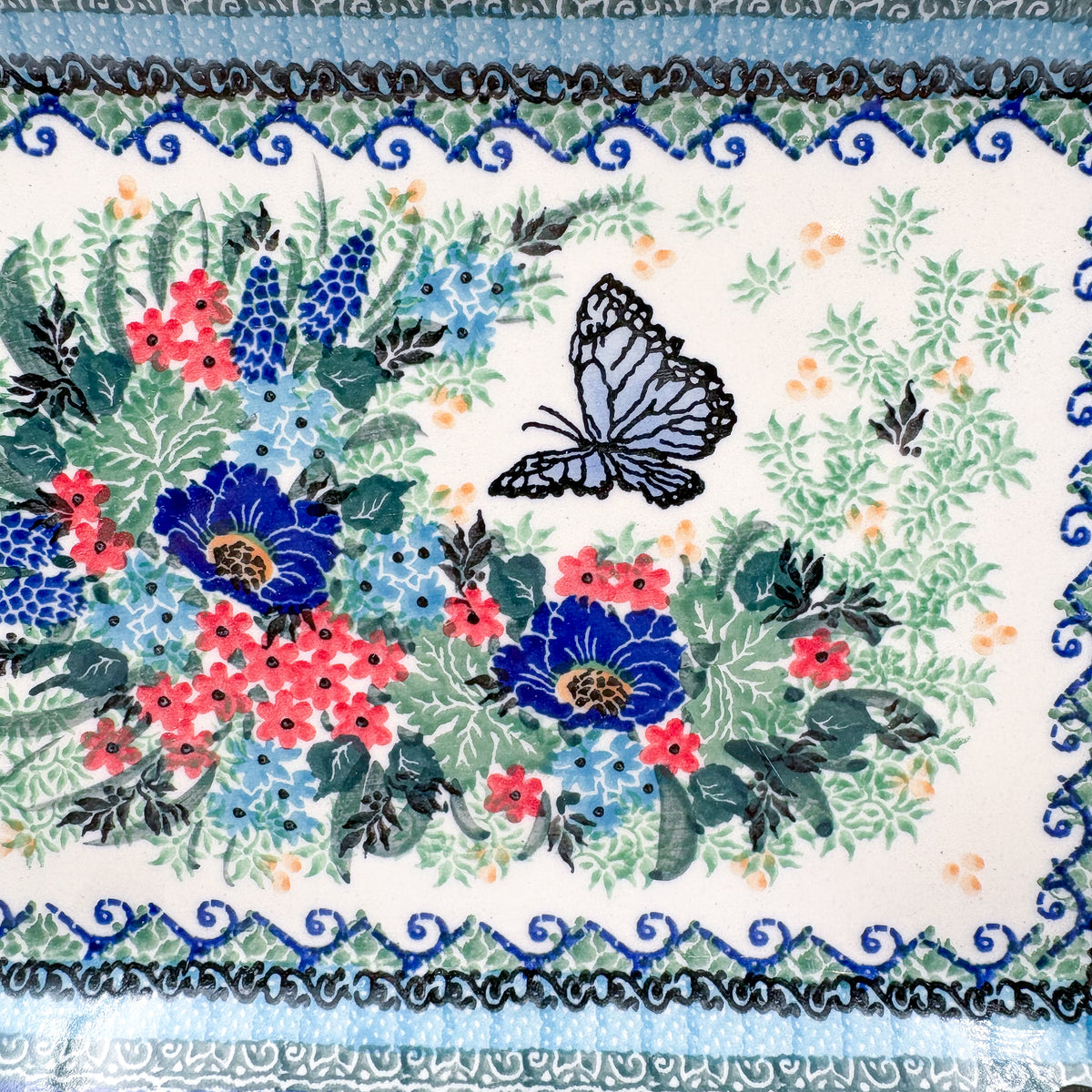 Mariposa rectangular platter, close-up top-down view of black butterfly and blue and pink floral bouquet