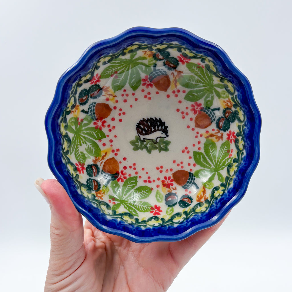 UNIKAT Hedgehog and Pumpkin scalloped bowl held in hand, top-down view of hedgehog surrounded by acorn and leaf wreath