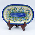 UNIKAT Bluebell Meadow oval platter, front view on stand showing bluebell field and mosaic center band