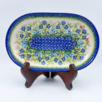 UNIKAT Bluebell Meadow oval platter, front view on stand showing bluebell field and mosaic center band