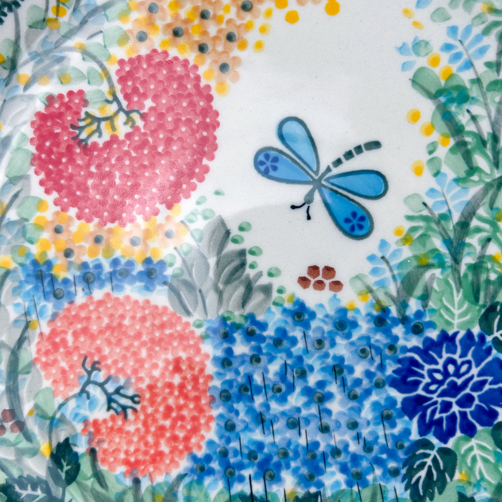 UNIKAT Garden Delight plate, close-up view of pink pom-pom flowers and blue dragonfly on garden pattern