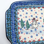 UNIKAT Snowman Stroll rectangular platter, close-up corner view of snowman, pine trees, and heart border pattern
