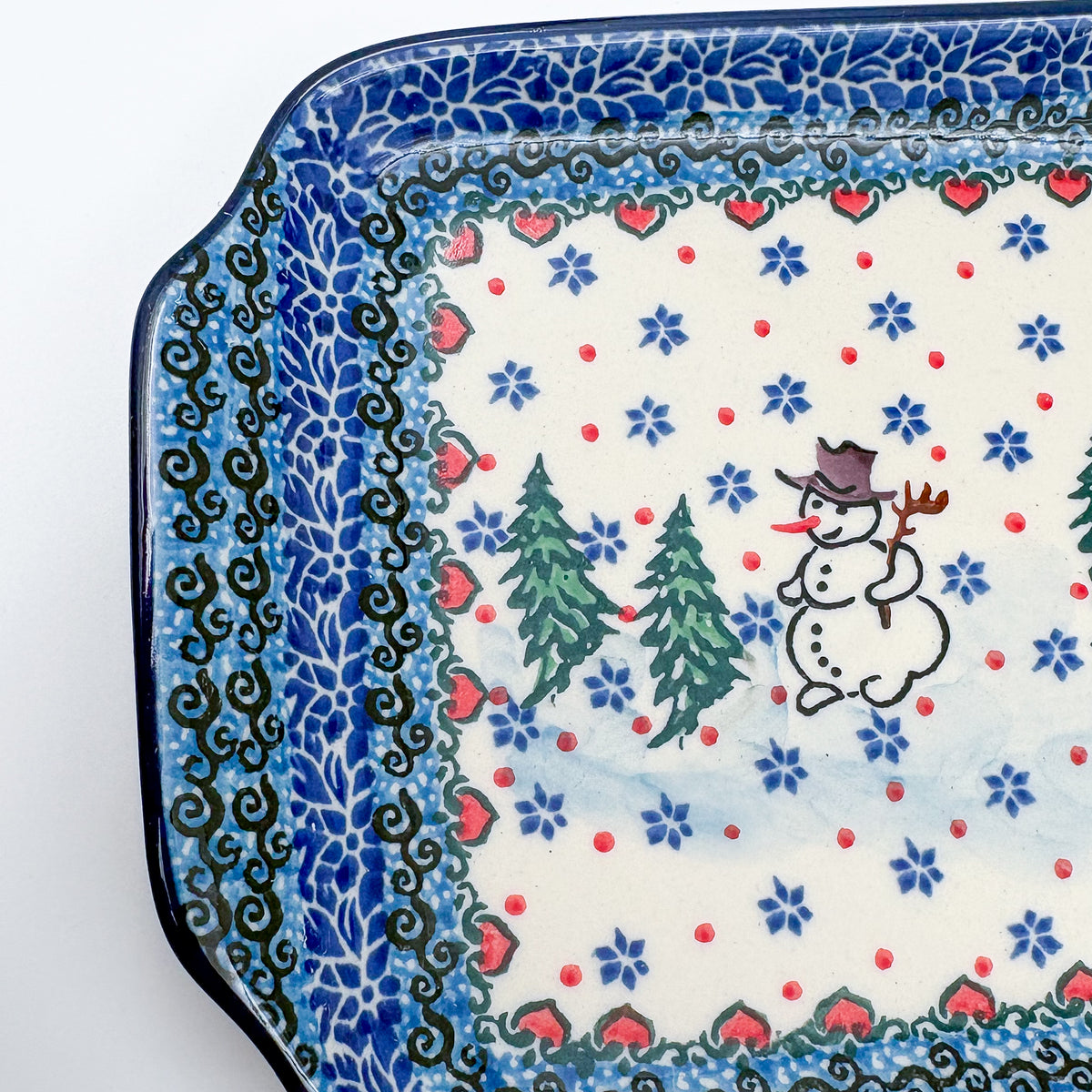 UNIKAT Snowman Stroll rectangular platter, close-up corner view of snowman, pine trees, and heart border pattern