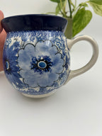 Blue Wildflower bubble mug held in hand, front view with plant in background