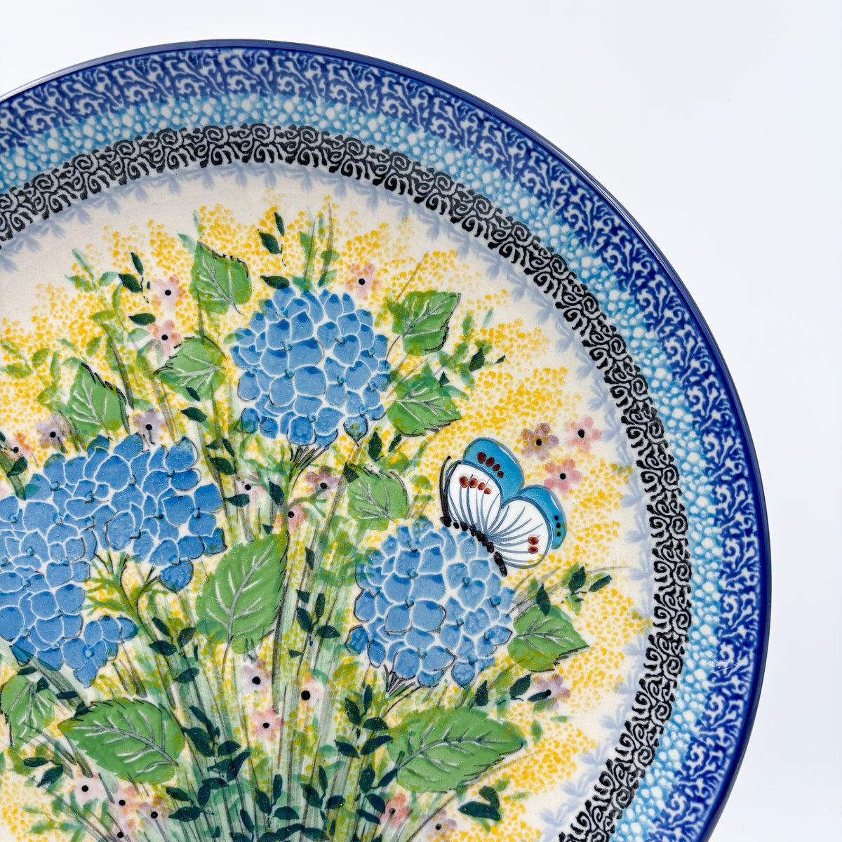 UNIKAT Blue Hydrangea plate, close-up rim view of blue hydrangea blooms and white butterfly