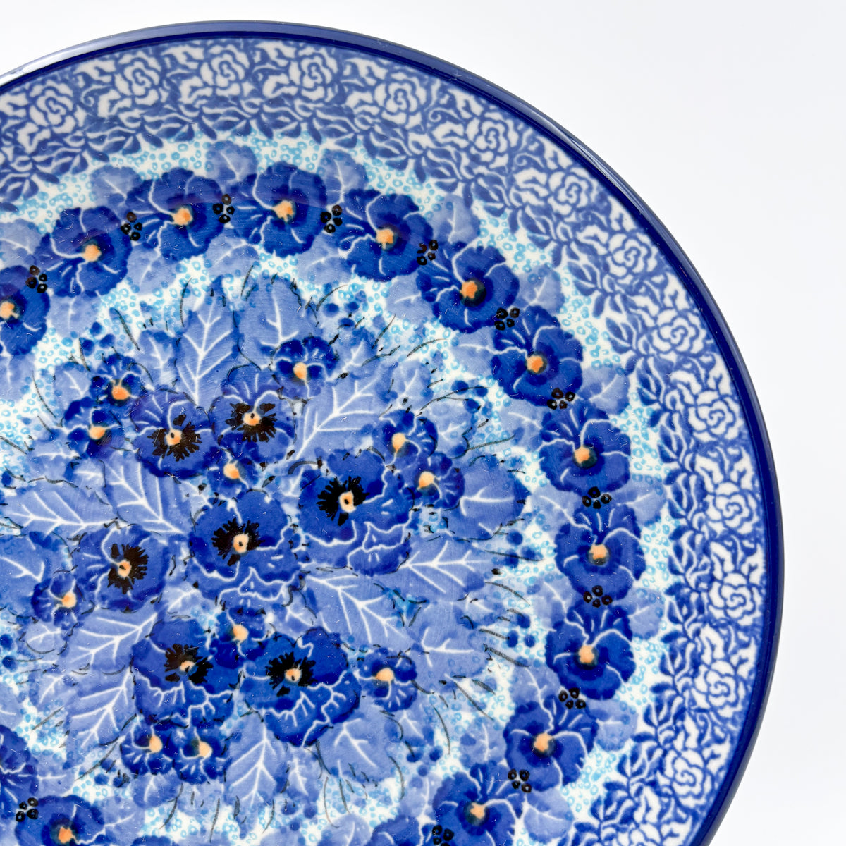 UNIKAT Deep Winter plate, close-up rim view showing rose border and blue pansy cluster