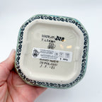 Bottom of Butterfly Garden square bowl showing Unikat stamp and artist signature, held in hand