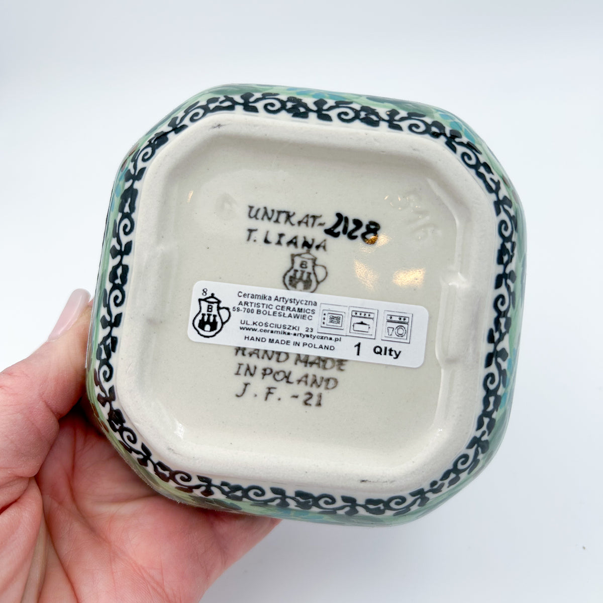 Bottom of Butterfly Garden square bowl showing Unikat stamp and artist signature, held in hand