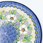 UNIKAT Primrose plate, close-up angled view of white poppy ring around blue dotted center