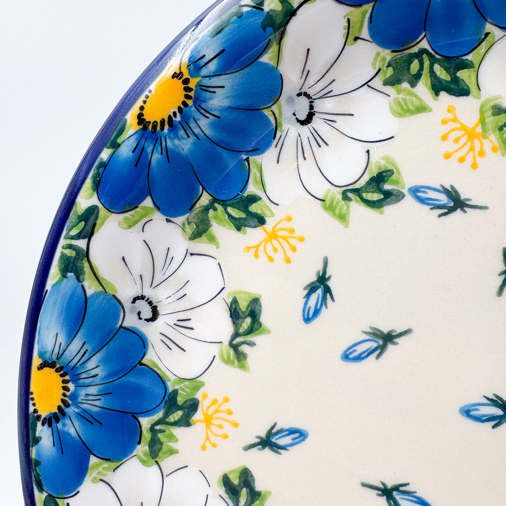 UNIKAT Blue Petal Dance plate, close-up rim detail showing blue and white daisy ring