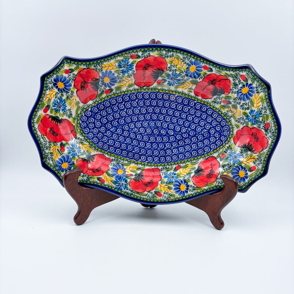 UNIKAT Garden Poppy Cezar platter, front view on stand showing red poppy border around blue spiral center