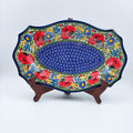 UNIKAT Garden Poppy Cezar platter, front view on stand showing red poppy border around blue spiral center
