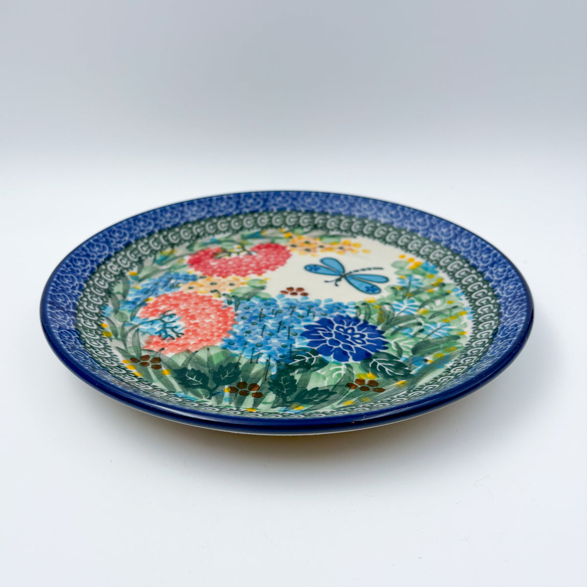 UNIKAT Garden Delight plate, front view showing pom-pom flowers, dahlia, and dragonfly on scalloped border