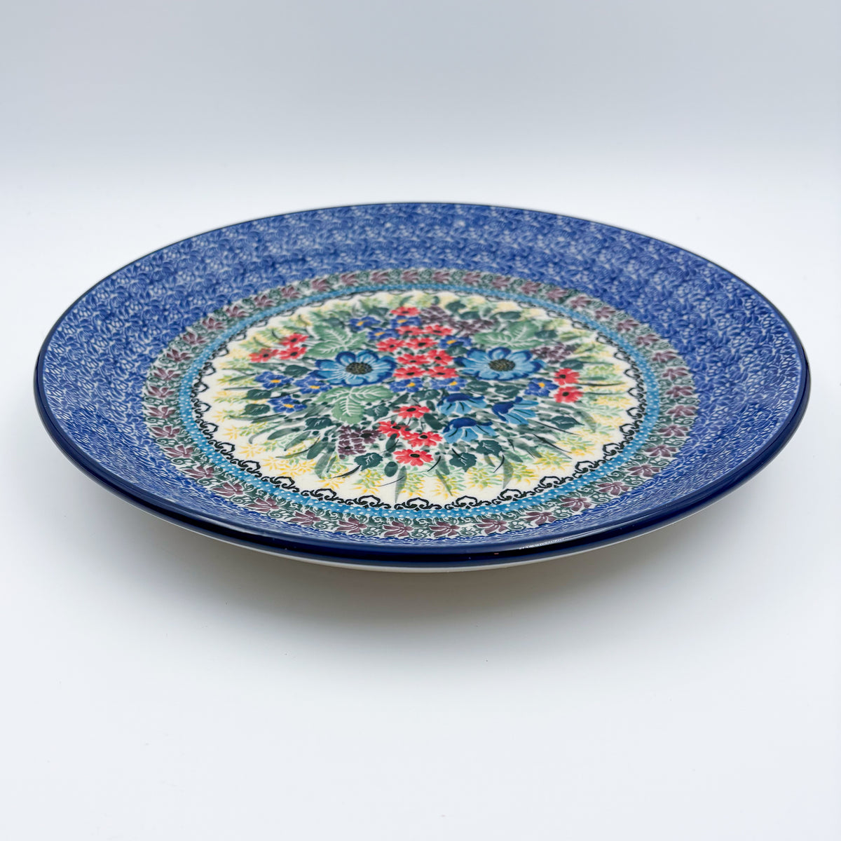 UNIKAT Splendid Meadow plate, front view showing red and blue floral bouquet and mosaic border