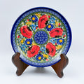UNIKAT Garden Poppy plate, front view displayed on wooden stand showing red poppy ring around blue spiral center