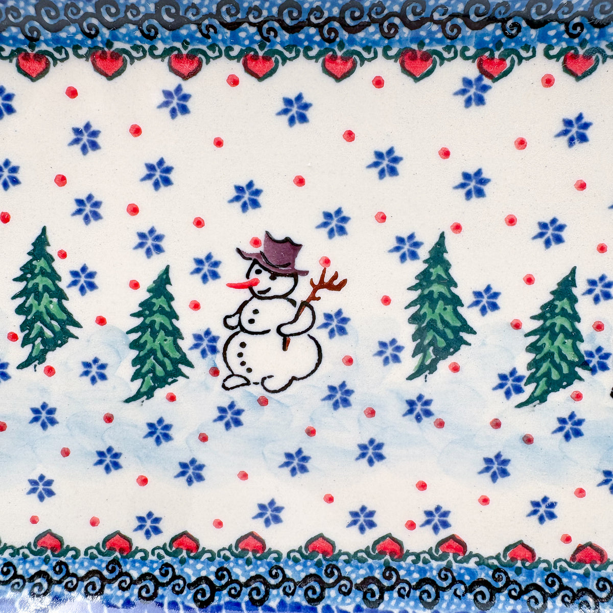 UNIKAT Snowman Stroll rectangular platter, close-up of single snowman with top hat and stick arms between pine trees