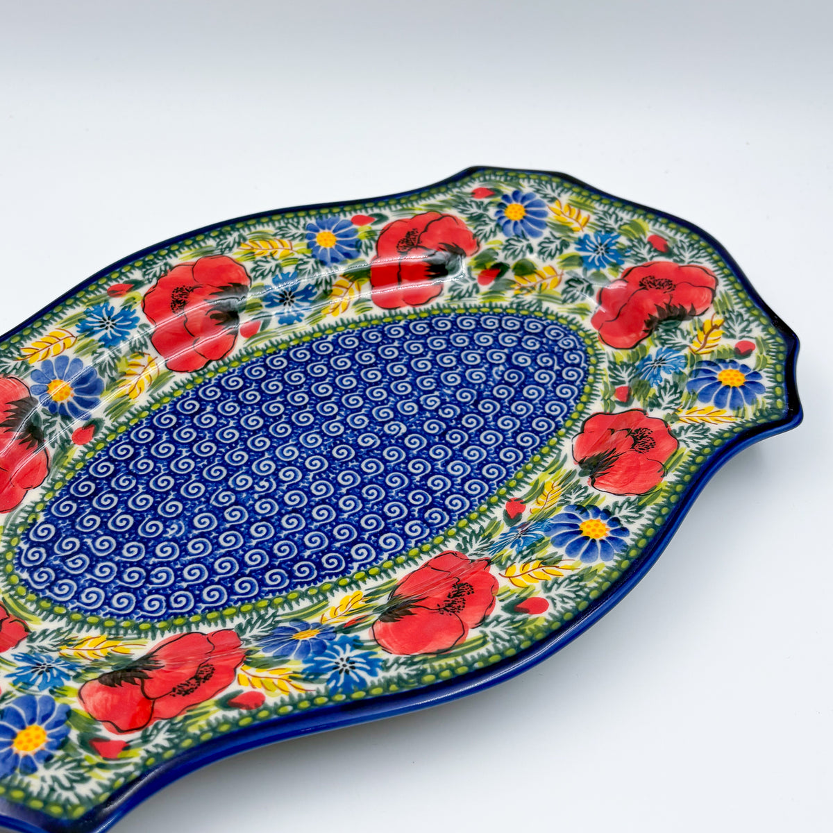 UNIKAT Garden Poppy Cezar platter, angled view of poppy border and blue spiral center