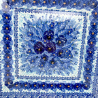 UNIKAT Deep Winter square plate, close-up top-down view of blue pansy bouquet center