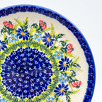 UNIKAT Meadow Breeze plate, close-up rim view showing blue and red wildflowers around navy mosaic center