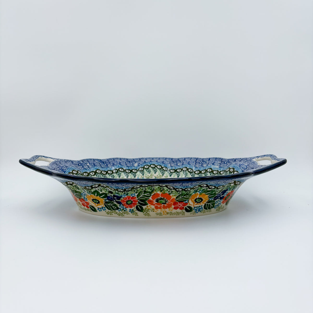 Iris Meadow oval platter with handles, straight-on side view showing cutout handles and exterior floral band