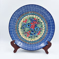 UNIKAT Splendid Meadow plate, front view displayed on wooden stand showing red and blue floral bouquet