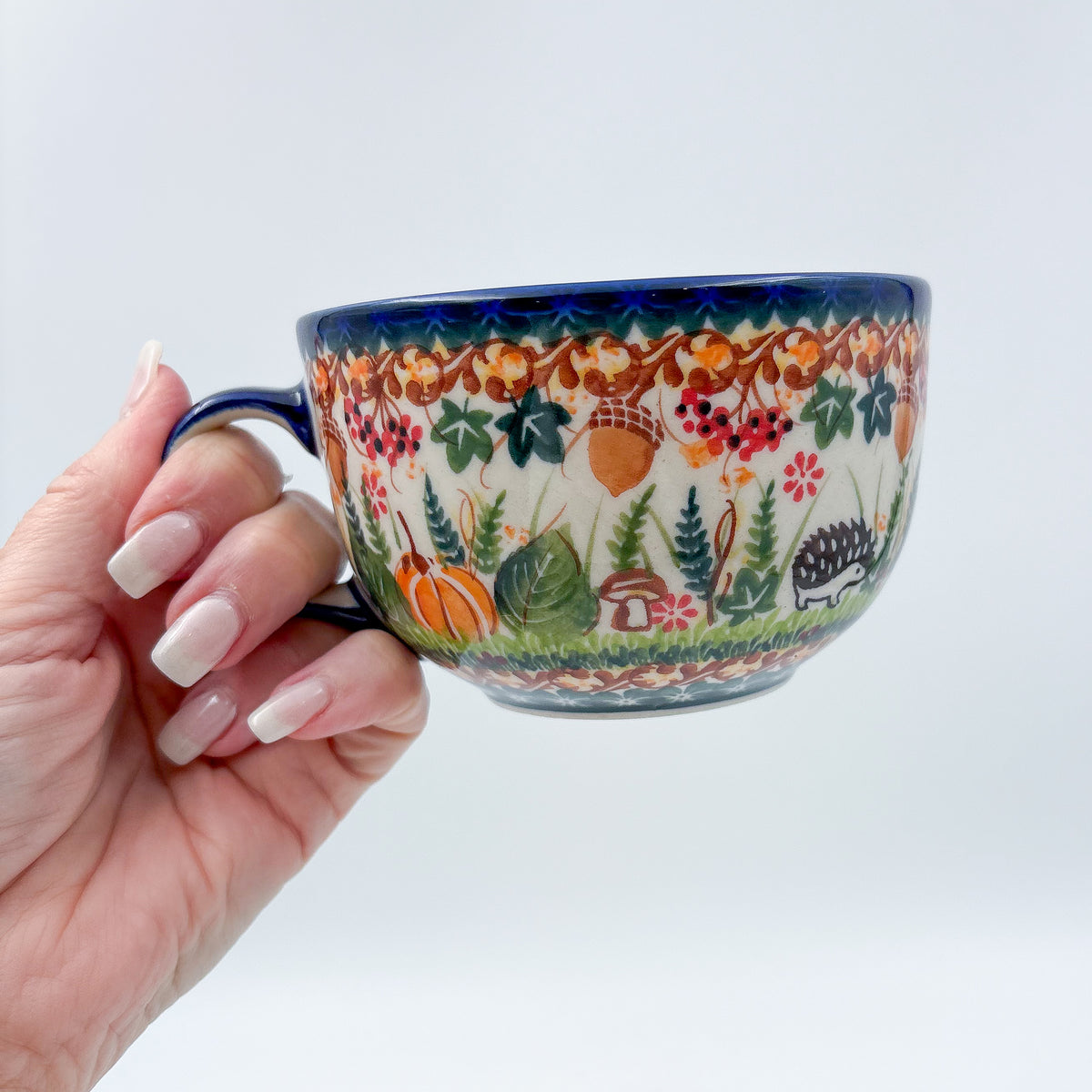 Hedgehog and Acorns latte mug held in hand, front view