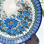 UNIKAT Blue Beauty plate, close-up view of blue daisy cluster and rim border displayed on stand