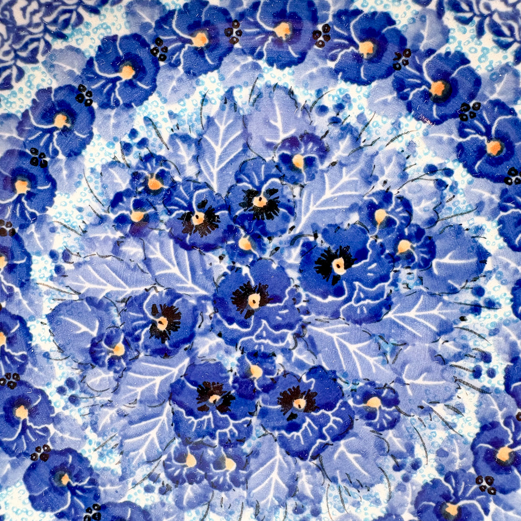 UNIKAT Deep Winter plate, close-up top-down view of blue pansy cluster center