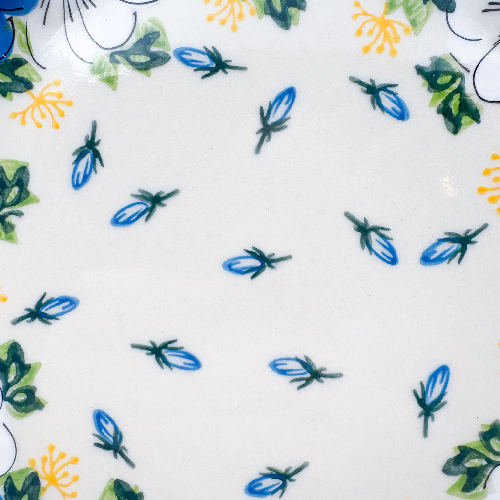 UNIKAT Blue Petal Dance plate, close-up top-down view of scattered blue petal accents on cream center