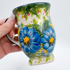 Blue Poppy Dance tulip mug held in hand, side view showing blue floral pattern
