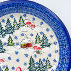 UNIKAT Gnome Village plate, close-up rim view showing snowy cabin and pine trees with mushrooms