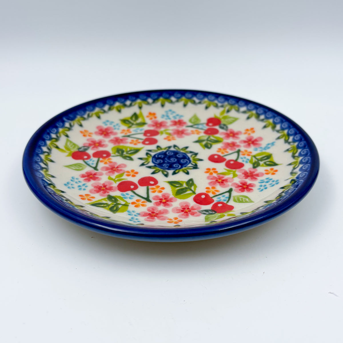 UNIKAT Cherry Blossom plate, front view showing red cherries and pink blossoms on scalloped rim