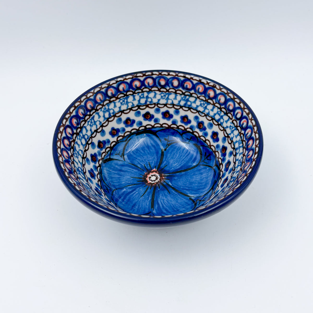 UNIKAT Cobalt Poppies bowl, front view showing blue poppy flower center with peacock feather rim pattern