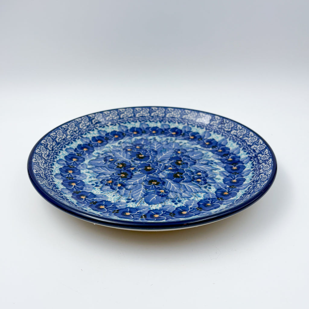 UNIKAT Deep Winter plate, front view showing blue pansy cluster on scalloped rim