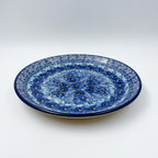 UNIKAT Deep Winter plate, front view showing blue pansy cluster on scalloped rim