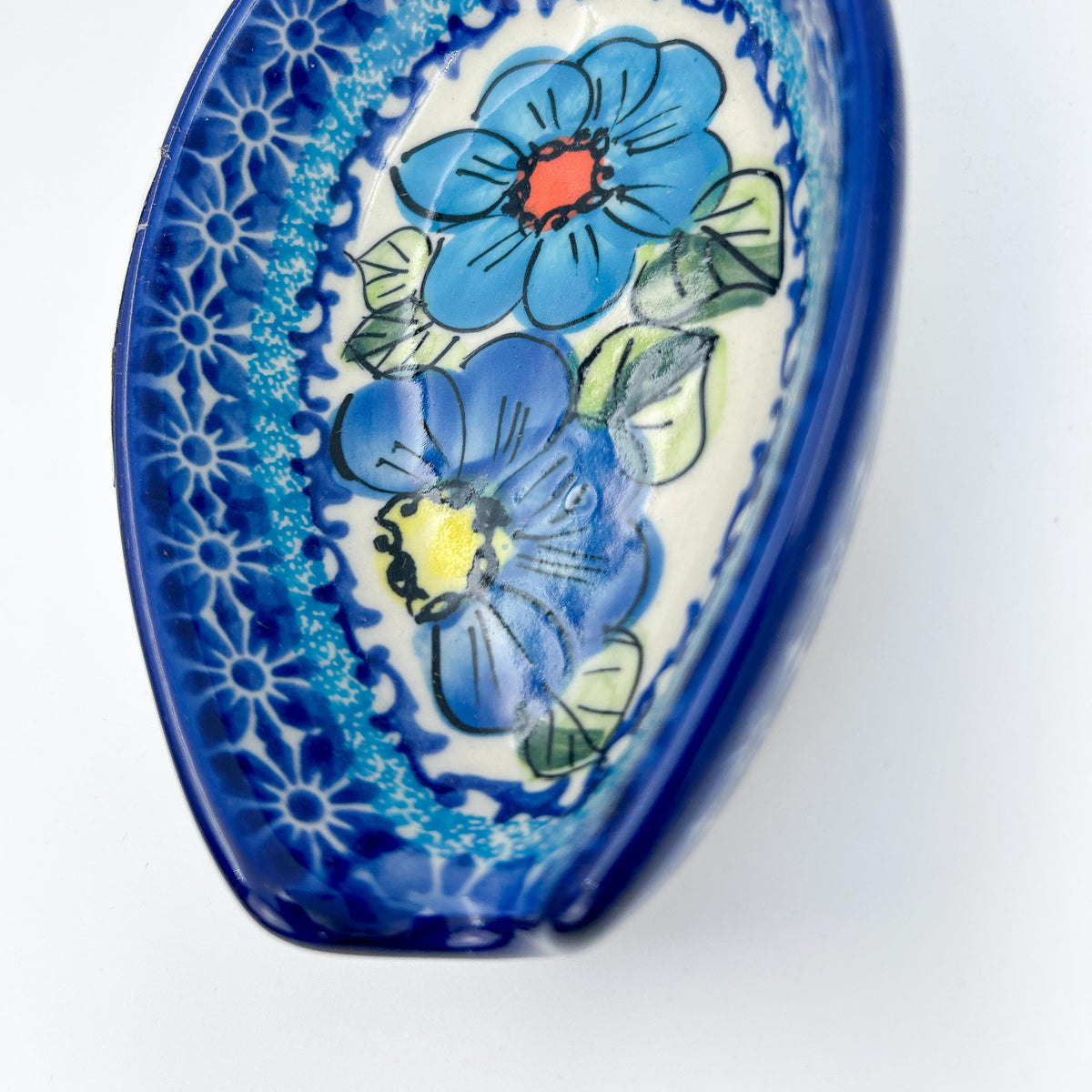 This 5” blue floral spoon rest is a handmade by talented Polish artisans. This is a Polish UNIKAT Bold Blue Poppies pattern 
Dimensions 5” x 3.54"
Ceramika BonaCompany