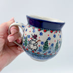 Snowman Stroll bubble mug held in hand, front view showing snowman and trees