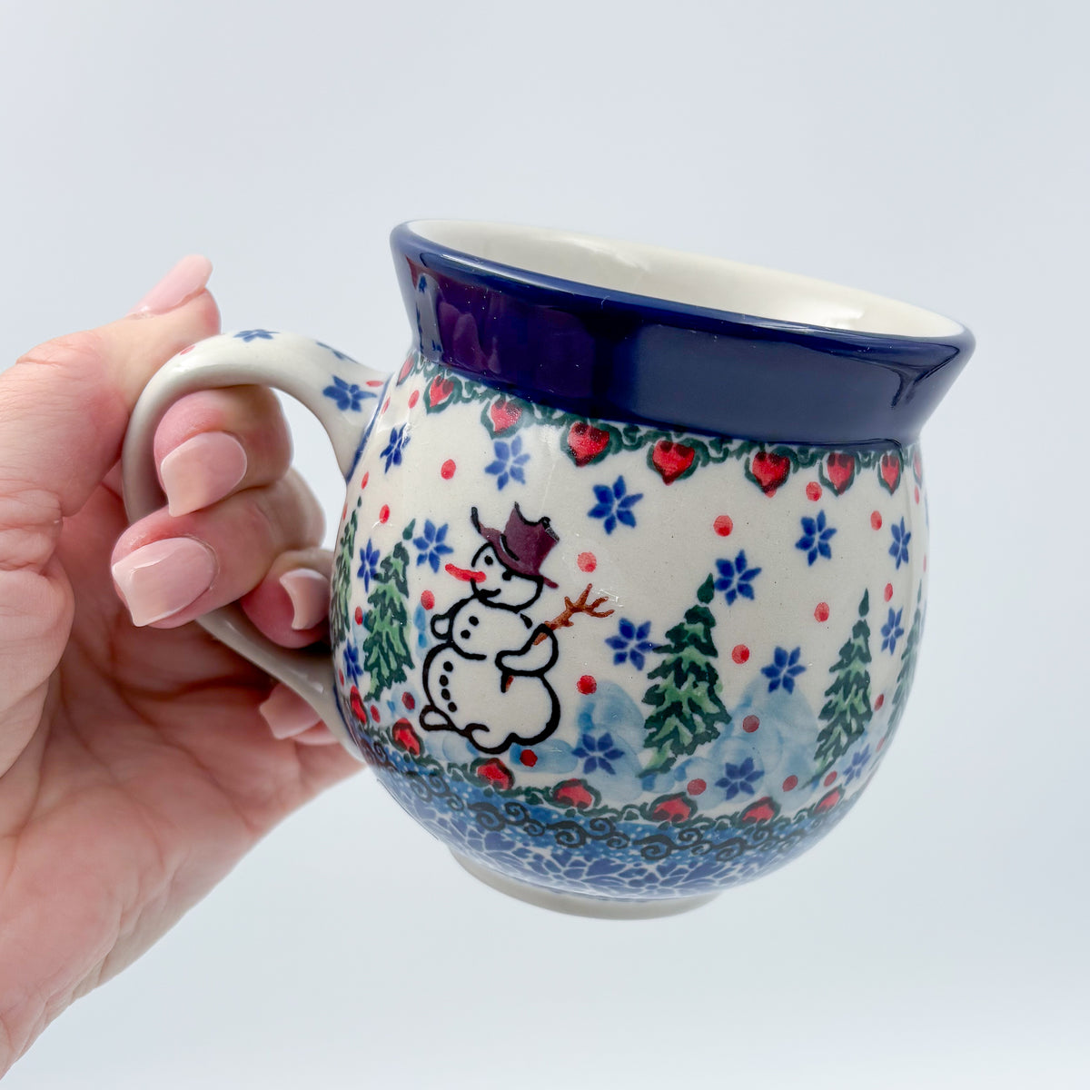 Snowman Stroll bubble mug held in hand, front view showing snowman and trees
