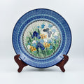 UNIKAT Sweet Nectar plate, front view displayed on wooden stand showing iris, yellow flowers, and butterfly