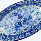 UNIKAT Deep Winter oval bowl, angled top-down close-up of blue pansy bouquet detail