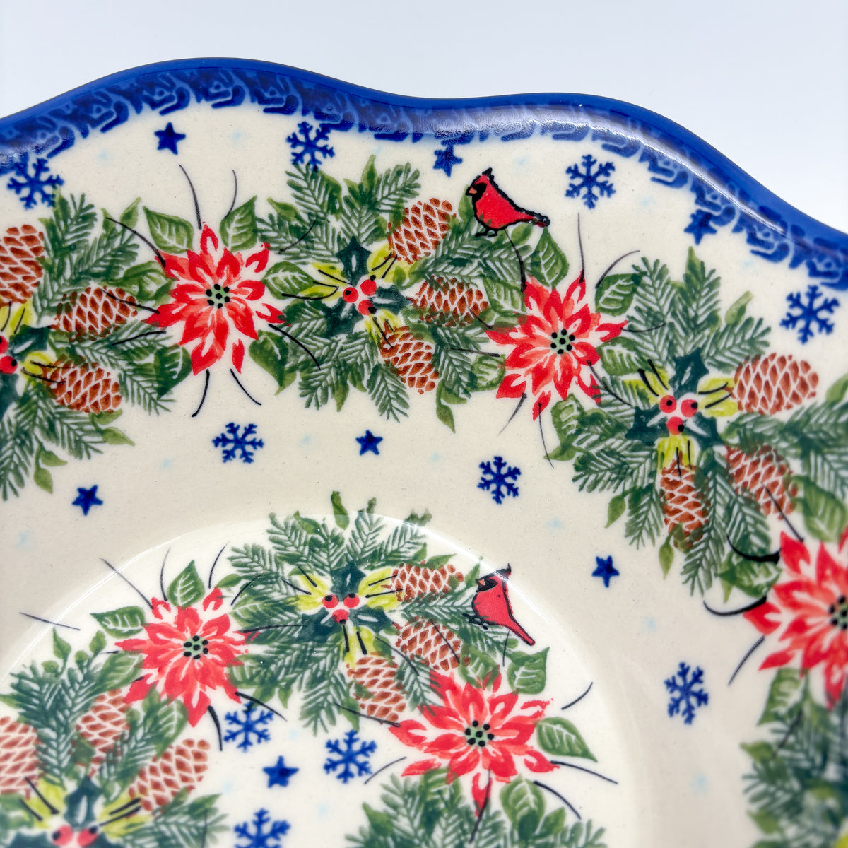 Christmas Cardinals wavy bowl, close-up rim detail showing cardinal, poinsettias, and blue snowflakes
