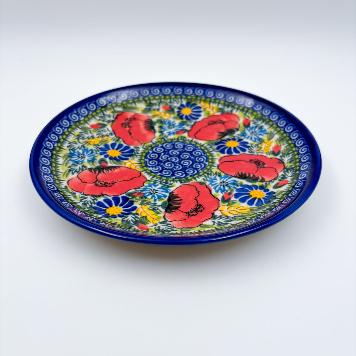UNIKAT Garden Poppy plate, front view showing red poppy ring around blue spiral center